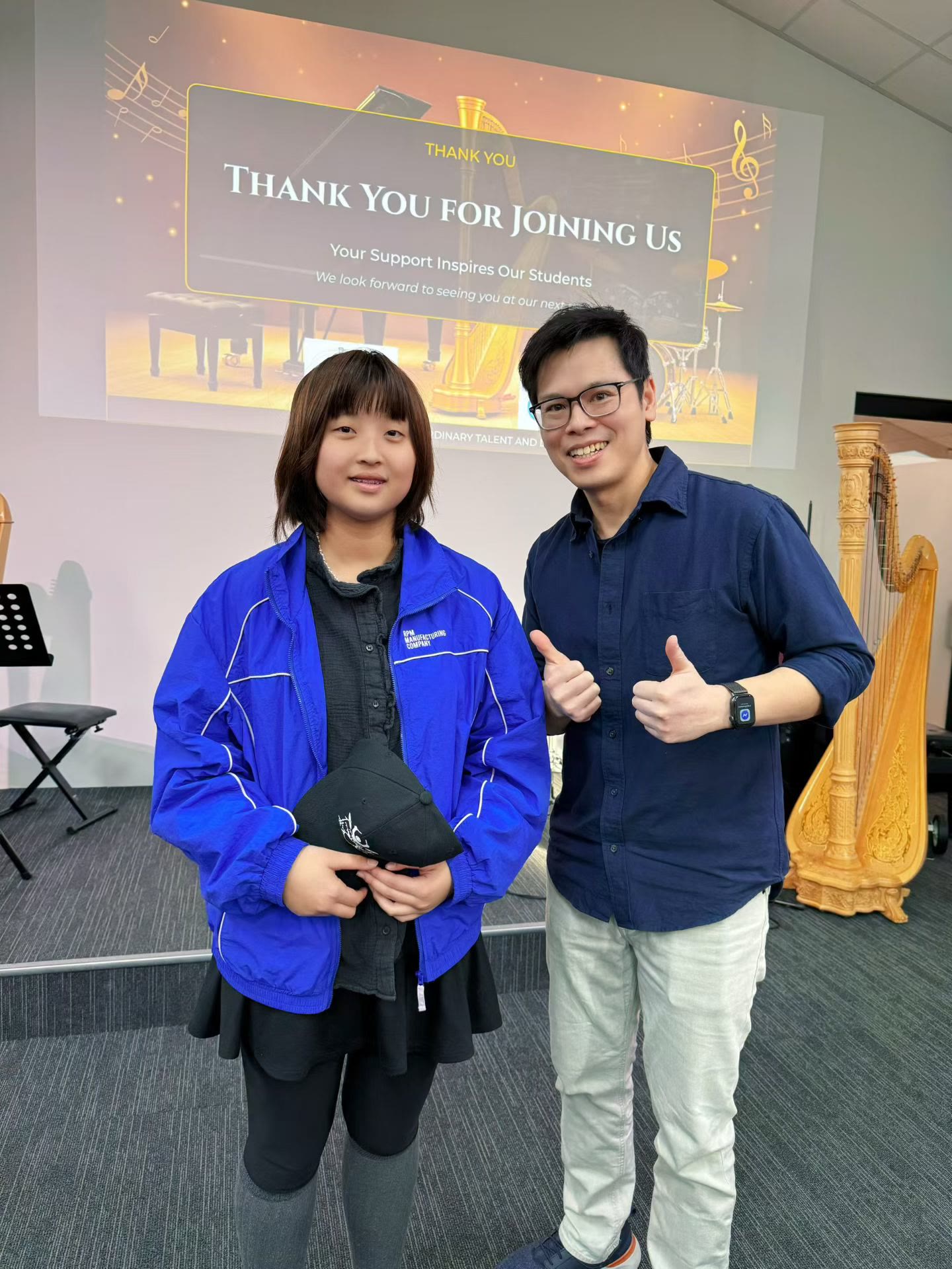 Isaac giving thumbs up with a student on stage at an iDrum Academy recital