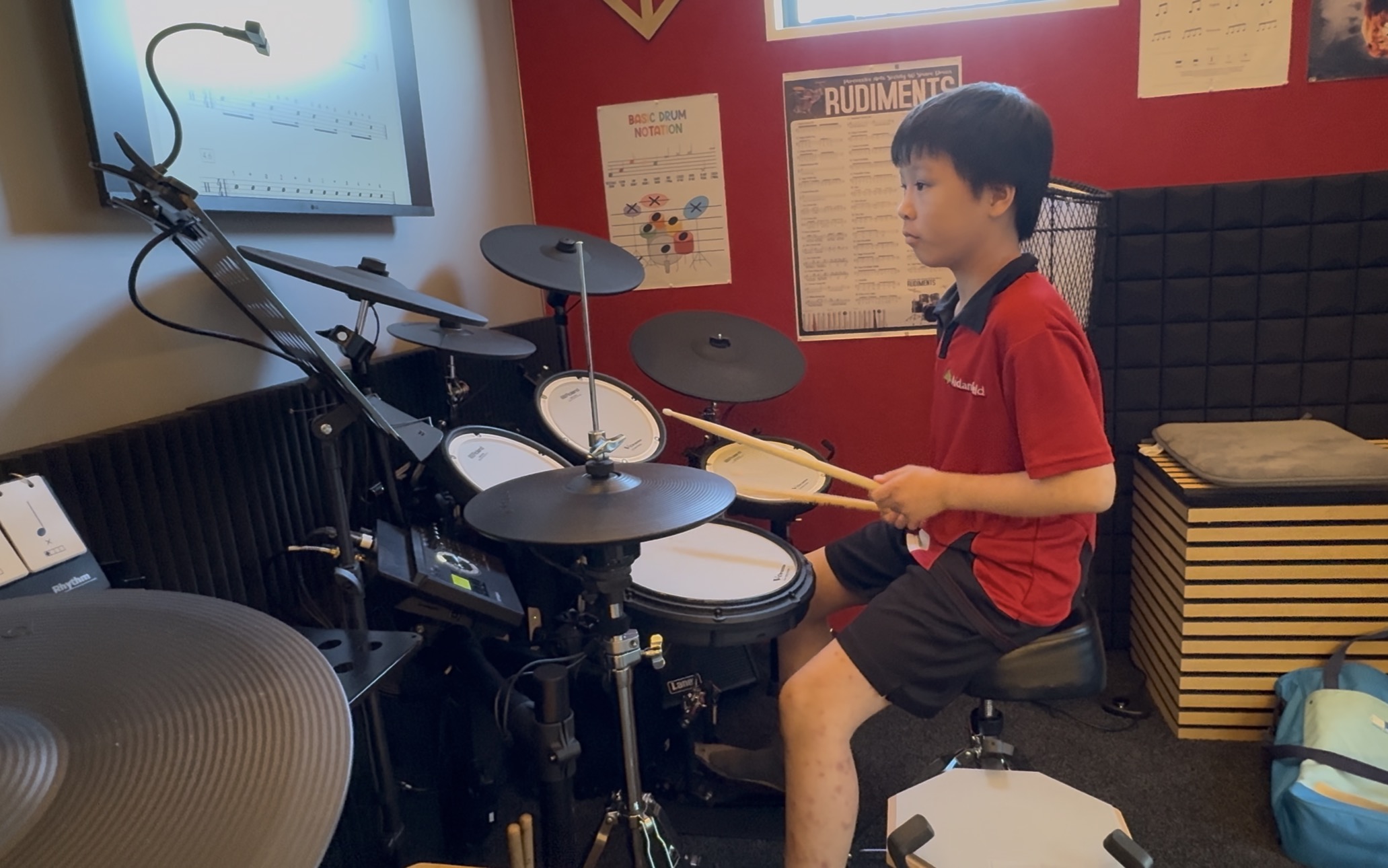 Young student playing drums in the studio with sheet music on a stand